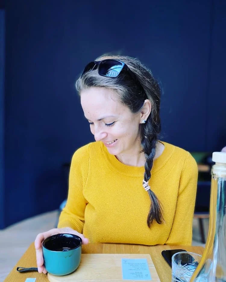 o tanara care rade uitandu-se in ceasca de cafea