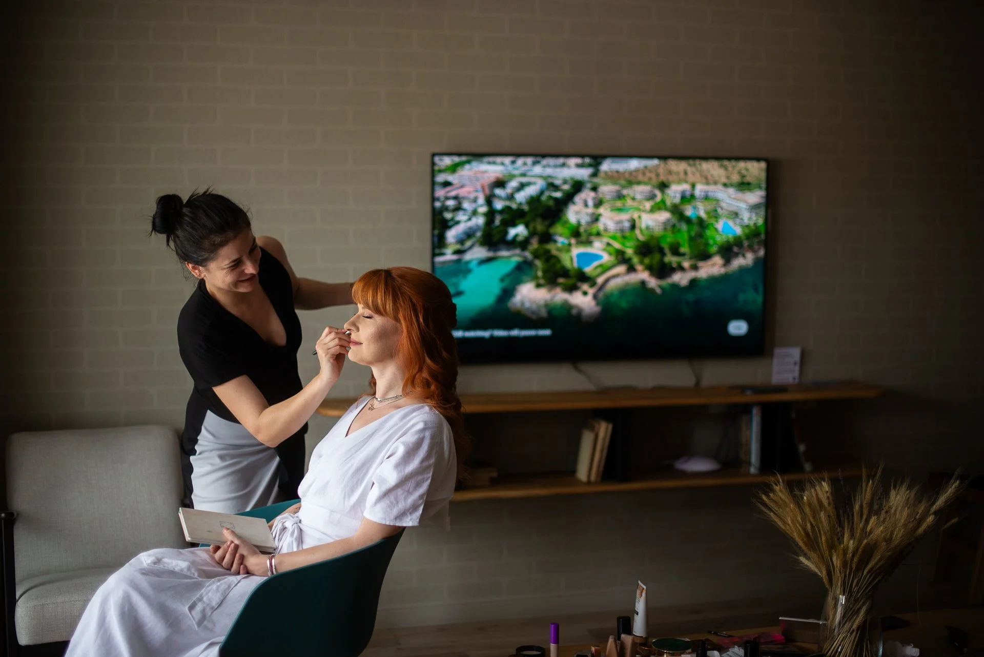 mireasa careia i se aplica machiajul pentru ziua nuntii in camera de hotel