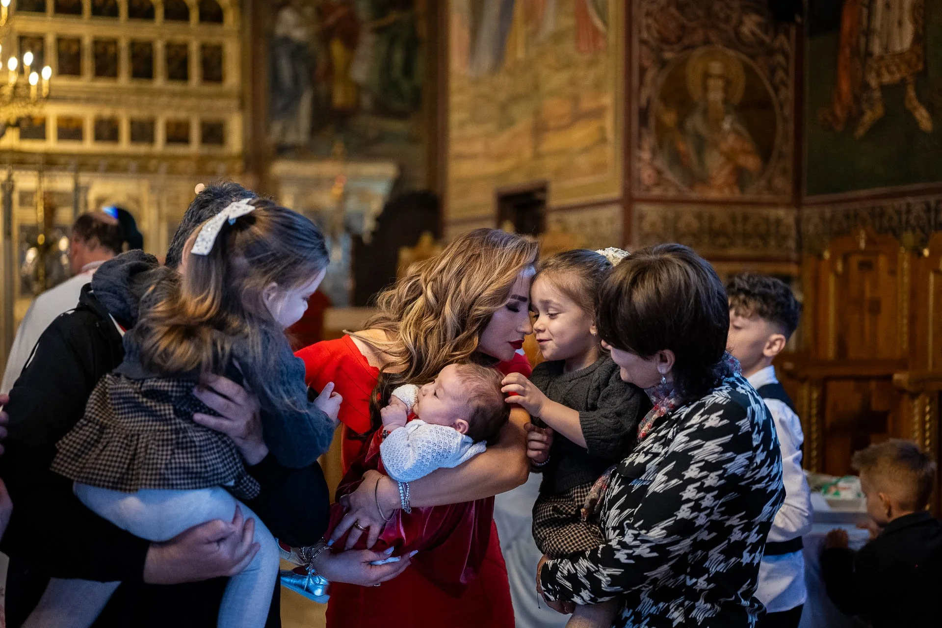 nasa tine in brate bebelusa care trebuie boteazata si sta cap in cap cu fetita ei tinunta in brate de bunica