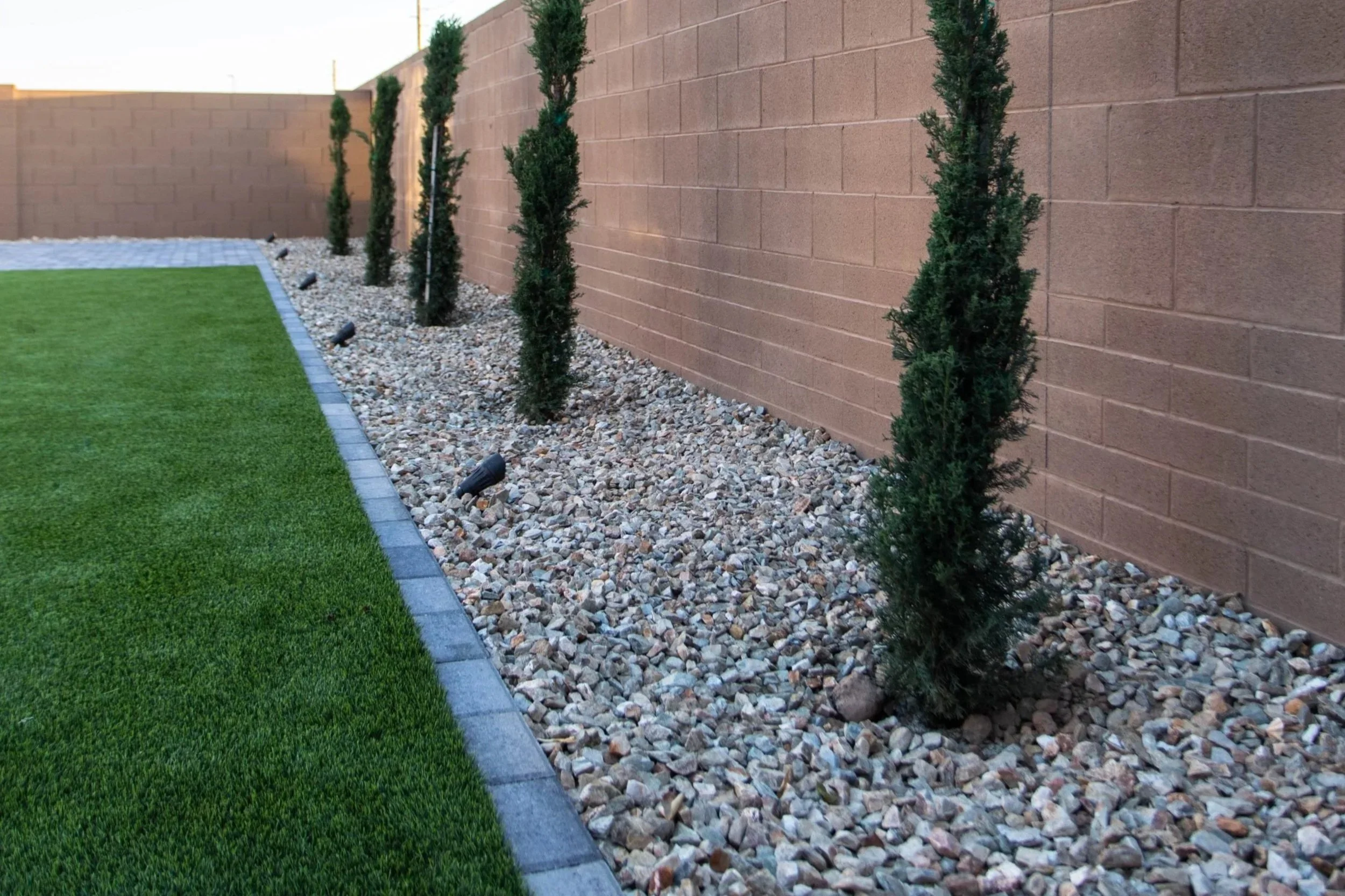 This residential backyard included turf, rock, tree and a paver border installation near Phoenix.