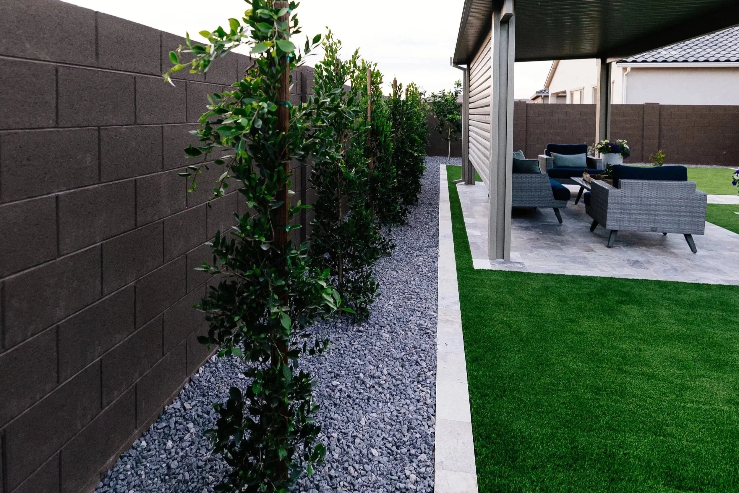 Rocks, trees, turf, travertine and a pergola installed at this new build construction home at the Blossom Rock community in Apache Junction by Better Life Landscape & Design