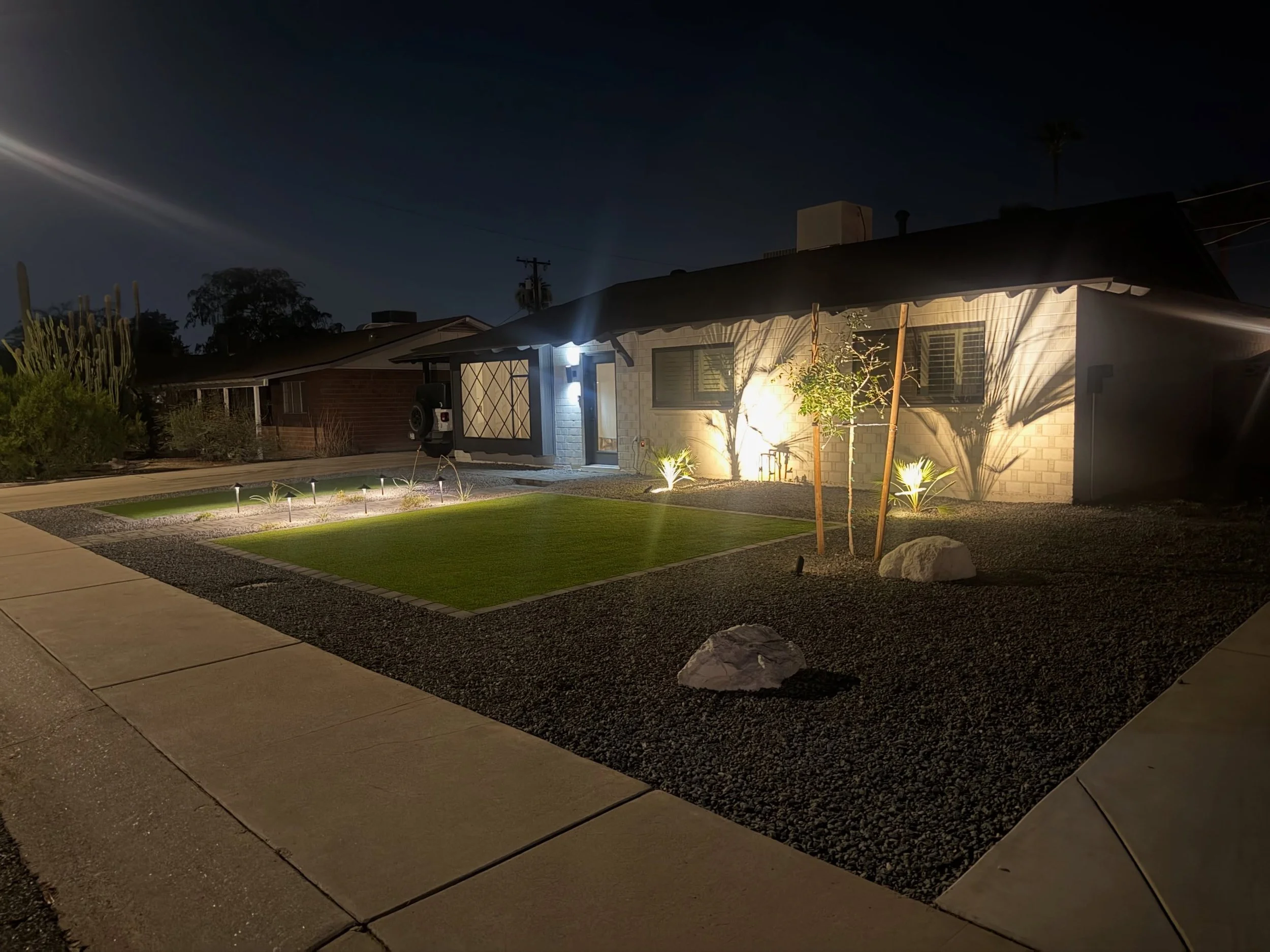 This front yard renovation included outdoor lighting along with turf, tree planting, rocks and a paver border installation by Better Life Landscape and Design, near Goodyear.
