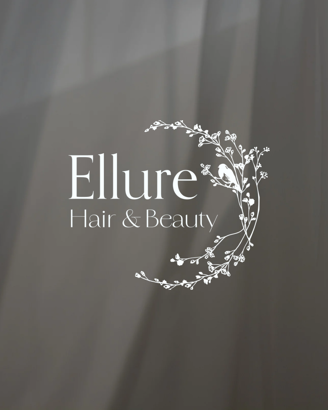 Sign for Ellure Hair & Beauty with decorative floral frame and silhouette of a bird in white on gray background.