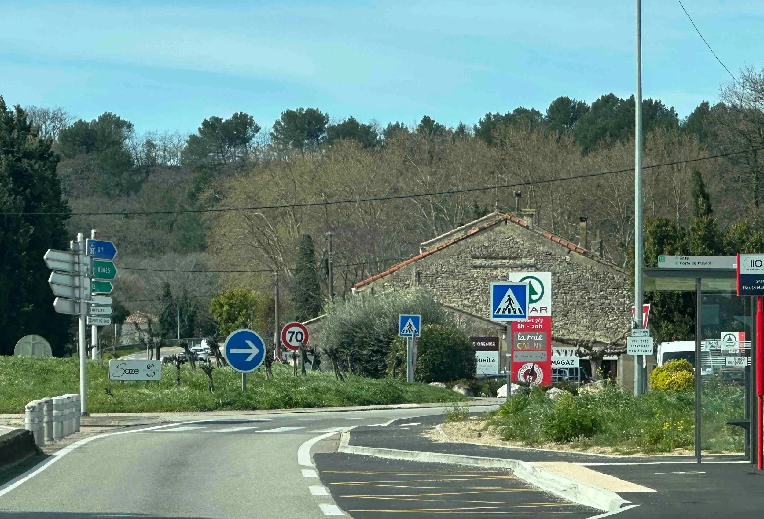 64 - Driving in another country is always an experience, particularly because the signs and road layouts are often different than in the US. Here we're approaching a traffic circle, with a bus stop at its entrance!