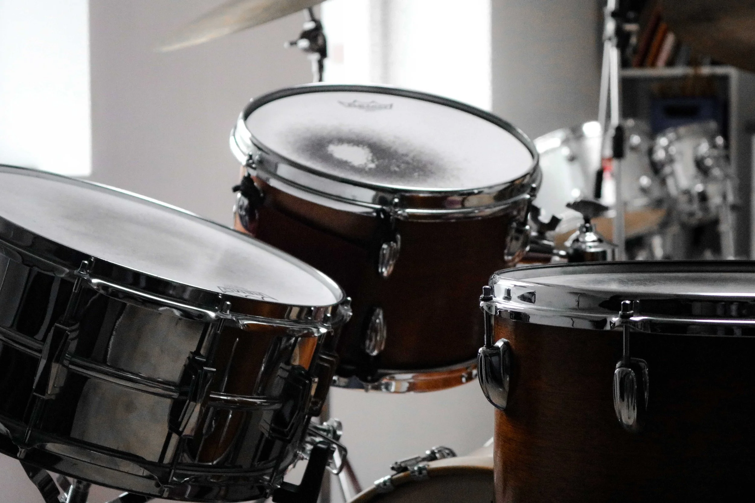 Close-up of a drum set with various drums and cymbals, including a snare, toms, and bass drum, in a music studio.