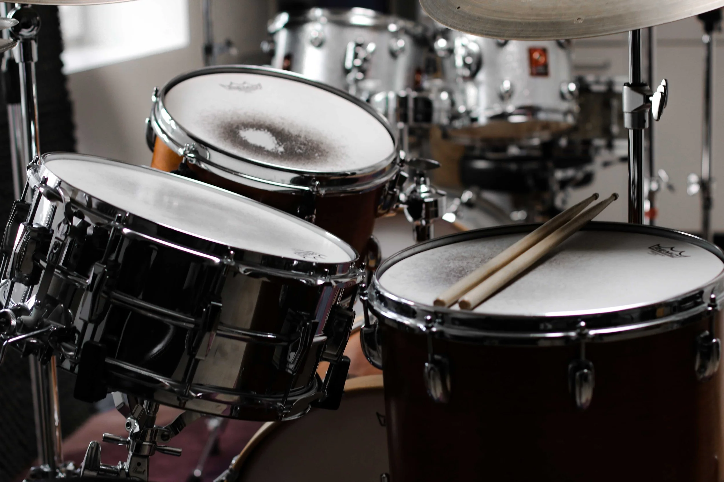 A close-up of a drum set with cymbals and wooden drumsticks resting on one of the drums.