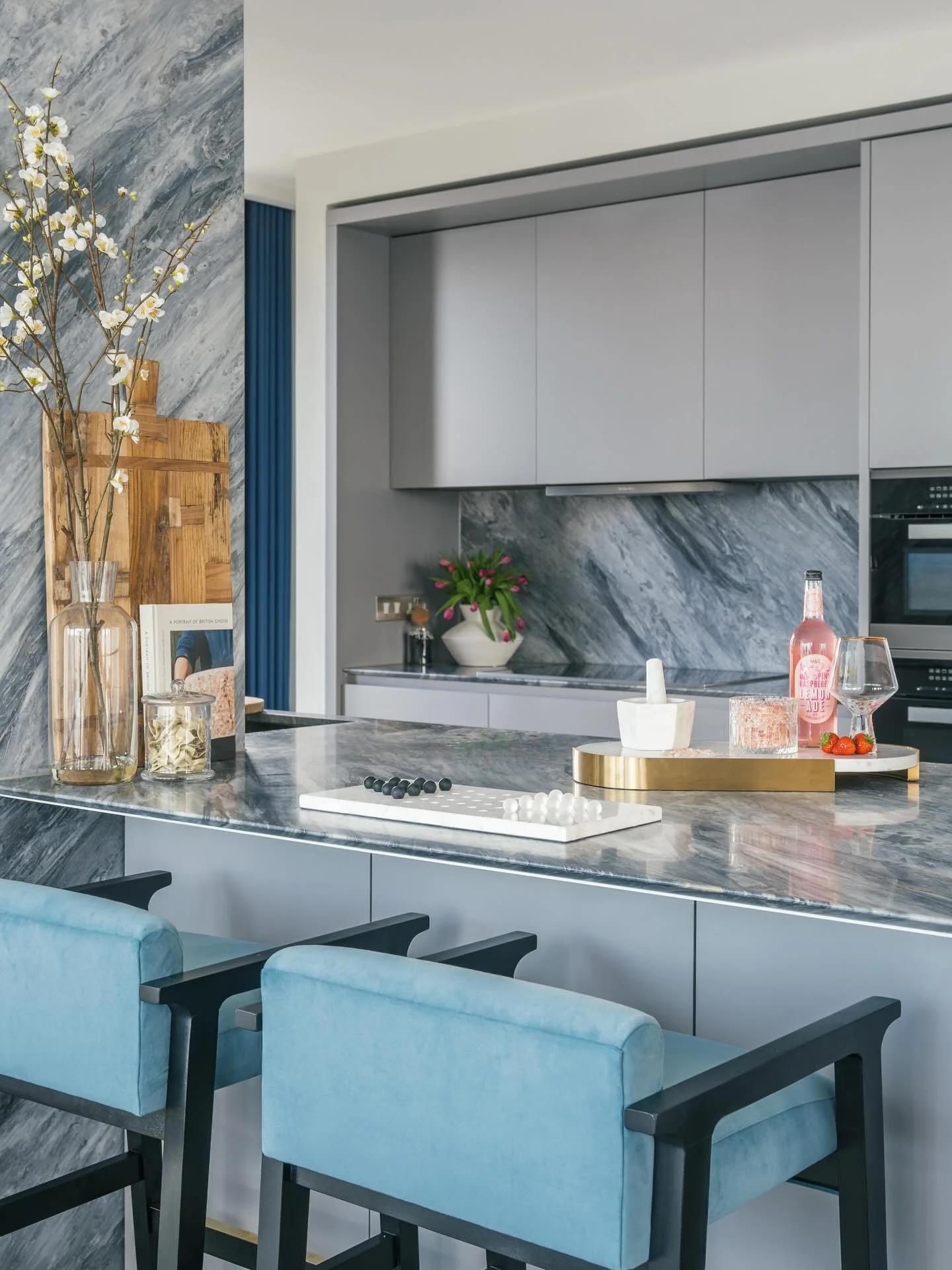 That Friday vibe!
We hope you&rsquo;ve all had a good week. 

Our showhome in the Sky Residences @onebgp giving us that Friday vibe ✨ 

Pietrasanta marble worktops and splashbacks complement our bespoke blue velvet bar stools with metal trim in this 