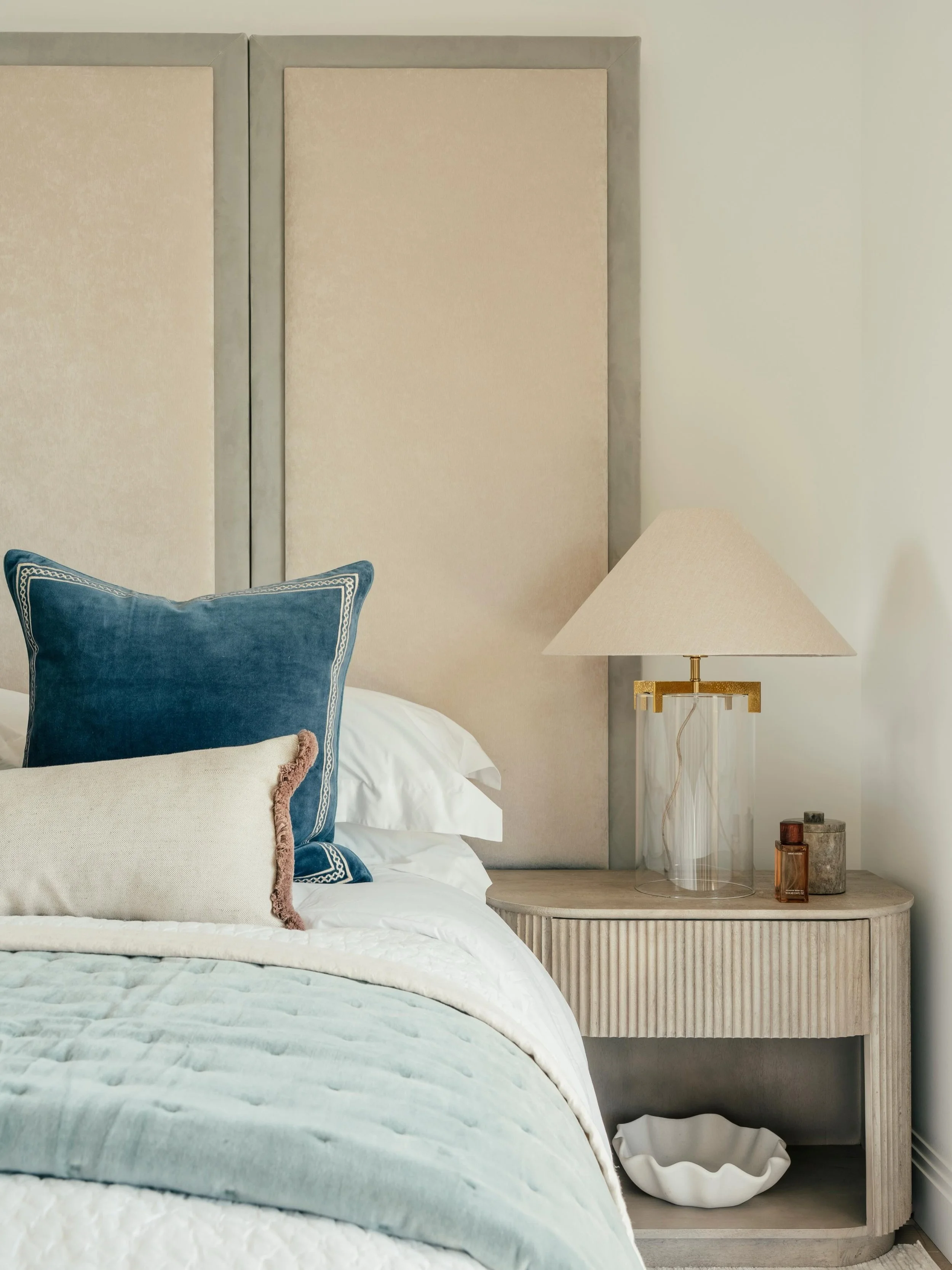 The calming palette of the principal bedroom in our latest Penthouse Showhome. 
A bespoke panelled headboard is paired with open bedside tables and glass lamps, creating a layered yet understated look. Velvet cushions from @oka finished with a subtle