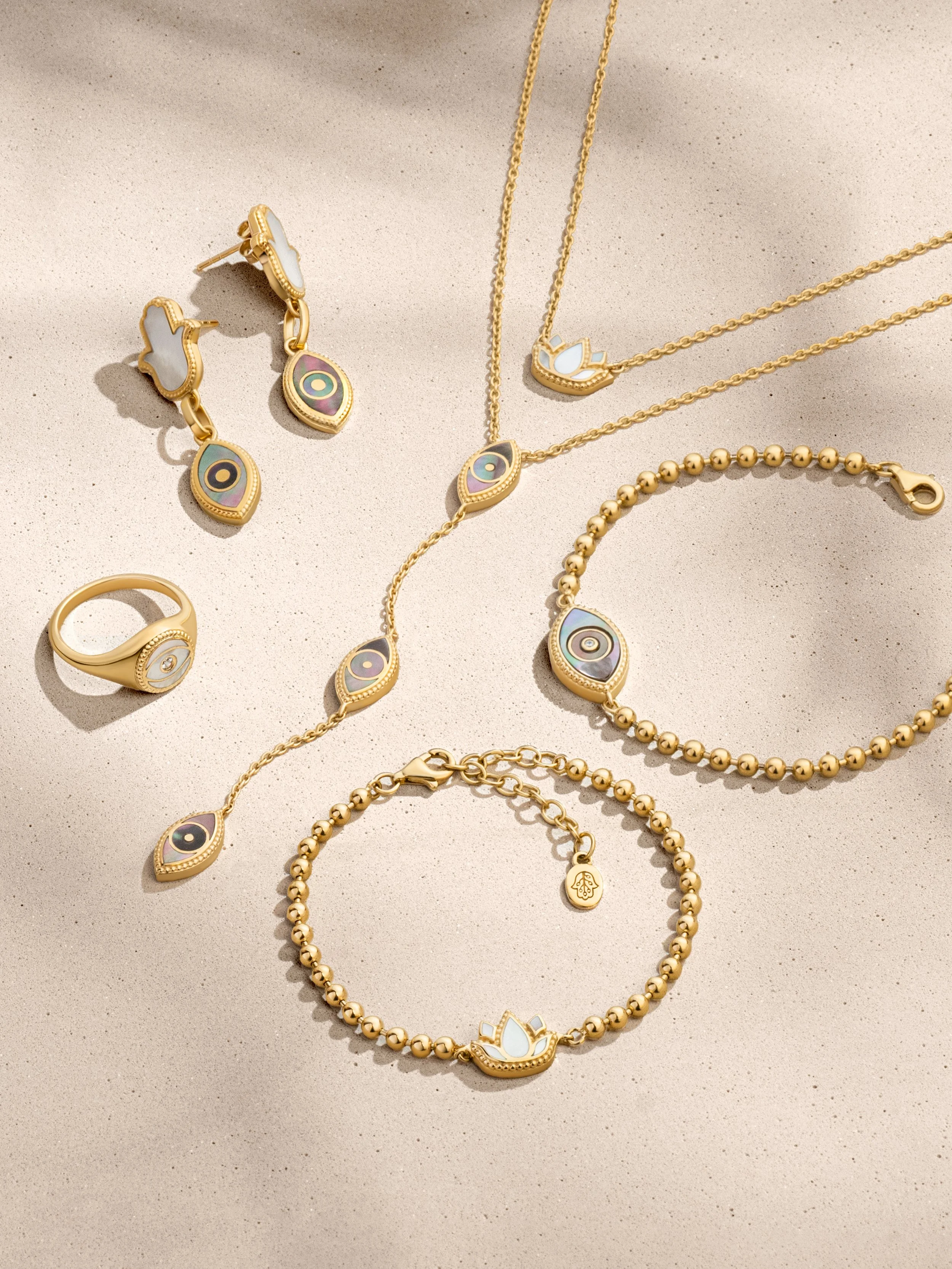 Collection of gold jewelry including earrings, necklaces, bracelets, and a ring, all featuring eye and lotus flower designs.