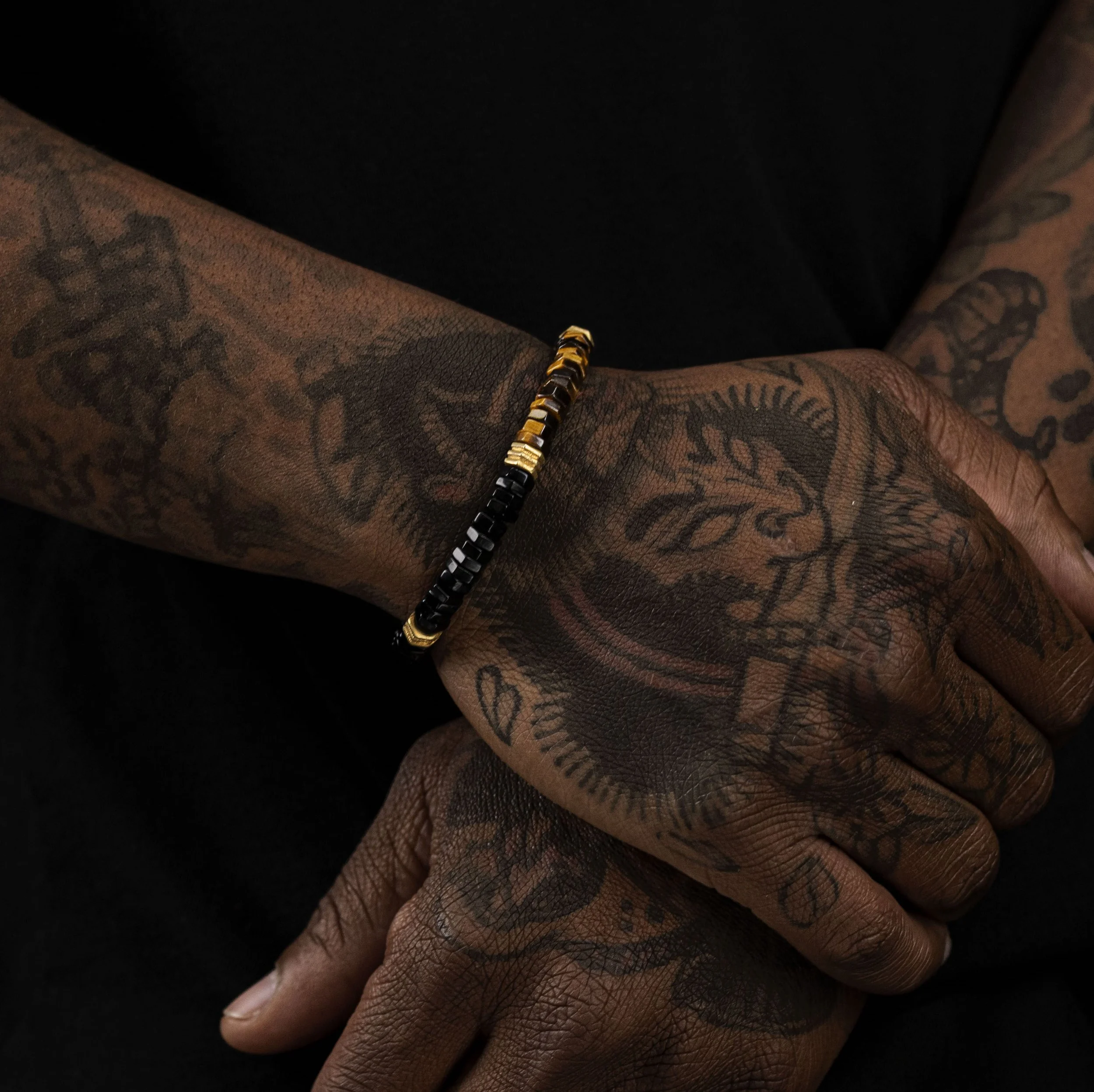 Macro shot of men wearing natural stone bracelets and tattoos
