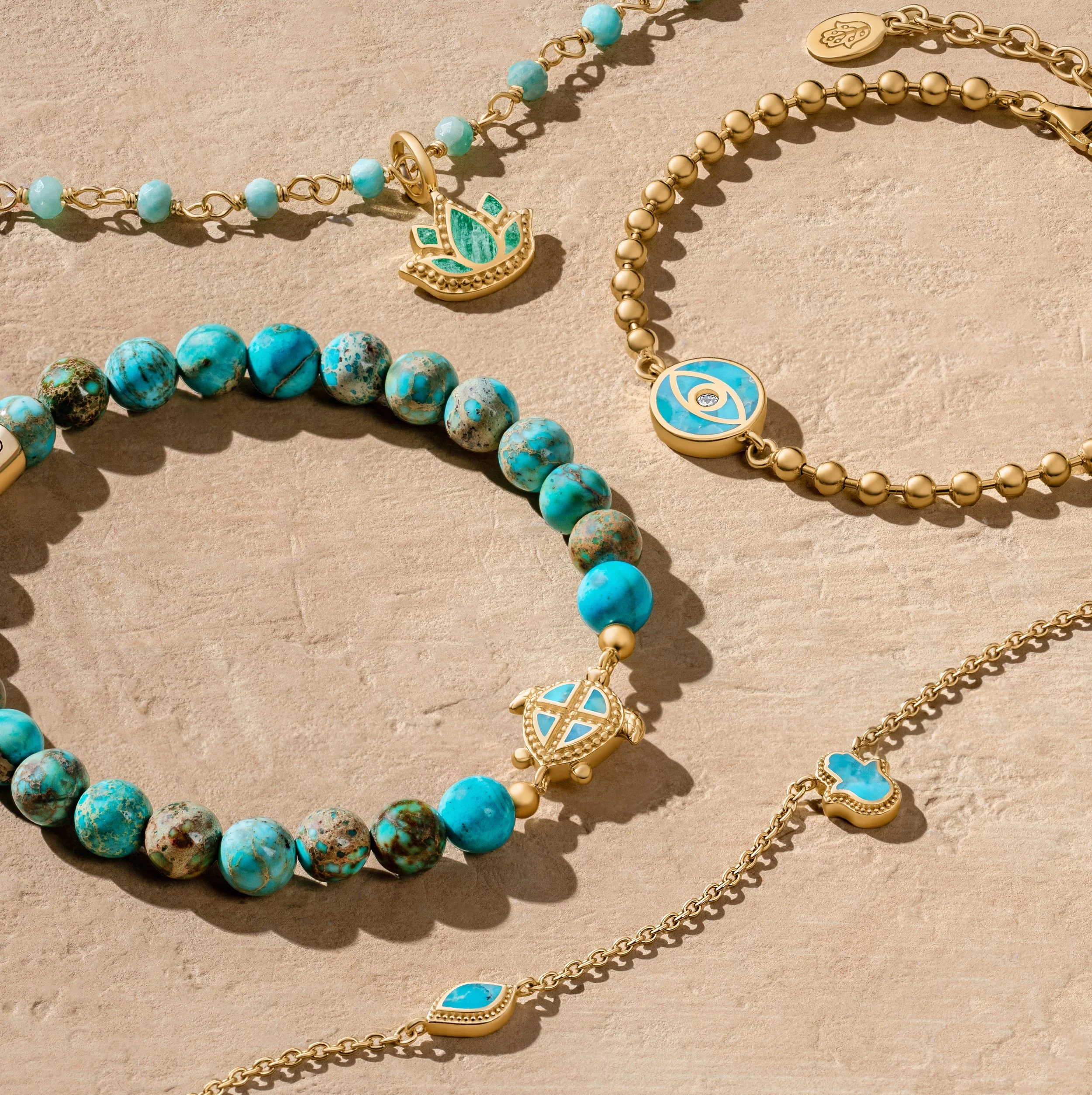 Collection of gold and turquoise jewelry including necklaces and bracelets on a beige surface.
