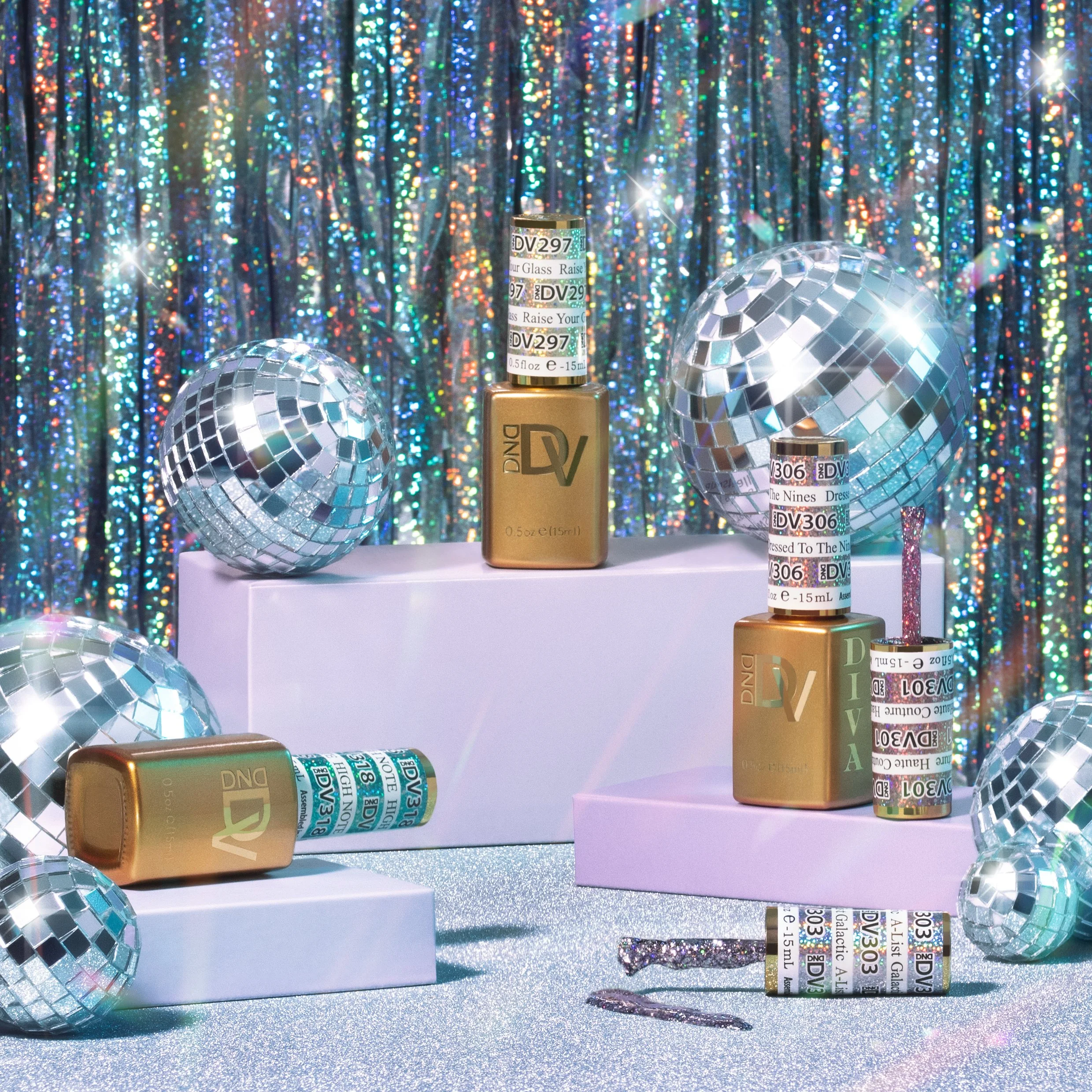 A colorful display of nail polish bottles with gold caps, surrounded by disco balls on a glittery surface with holographic curtains in the background.