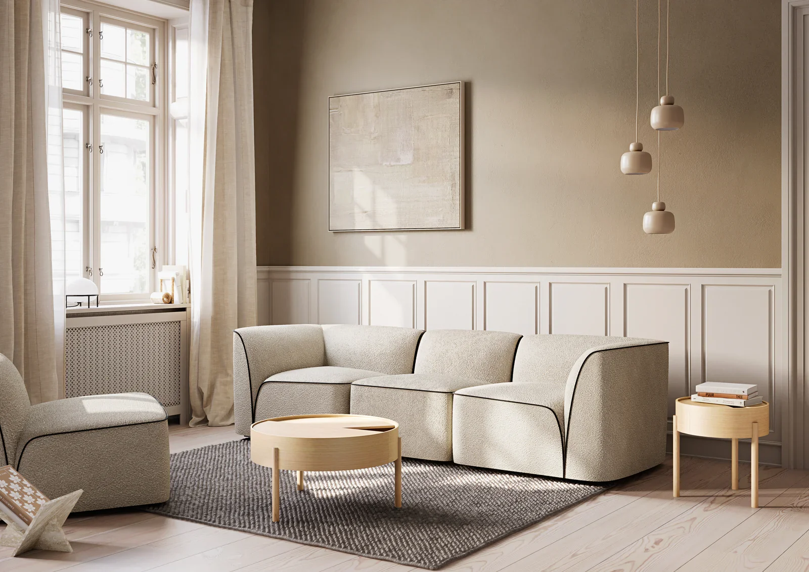 Bright, minimalist living room with beige L-shaped sofa, round wooden coffee table, small side table with books, large window with cream curtains, framed artwork on the wall, and modern pendant lights.