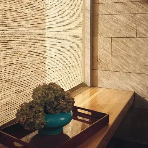 A wooden tray with a blue vase holding dried flowers on a wooden surface near textured and tiled walls.