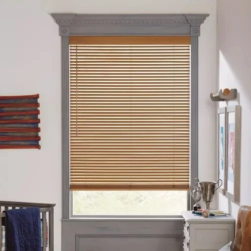 A window with beige horizontal blinds in a room with white walls and decorative gray trim.