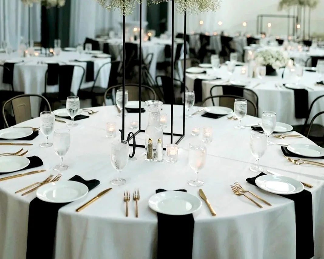 Silverware with plates, gold utensils and black napkins in waterfall fold.