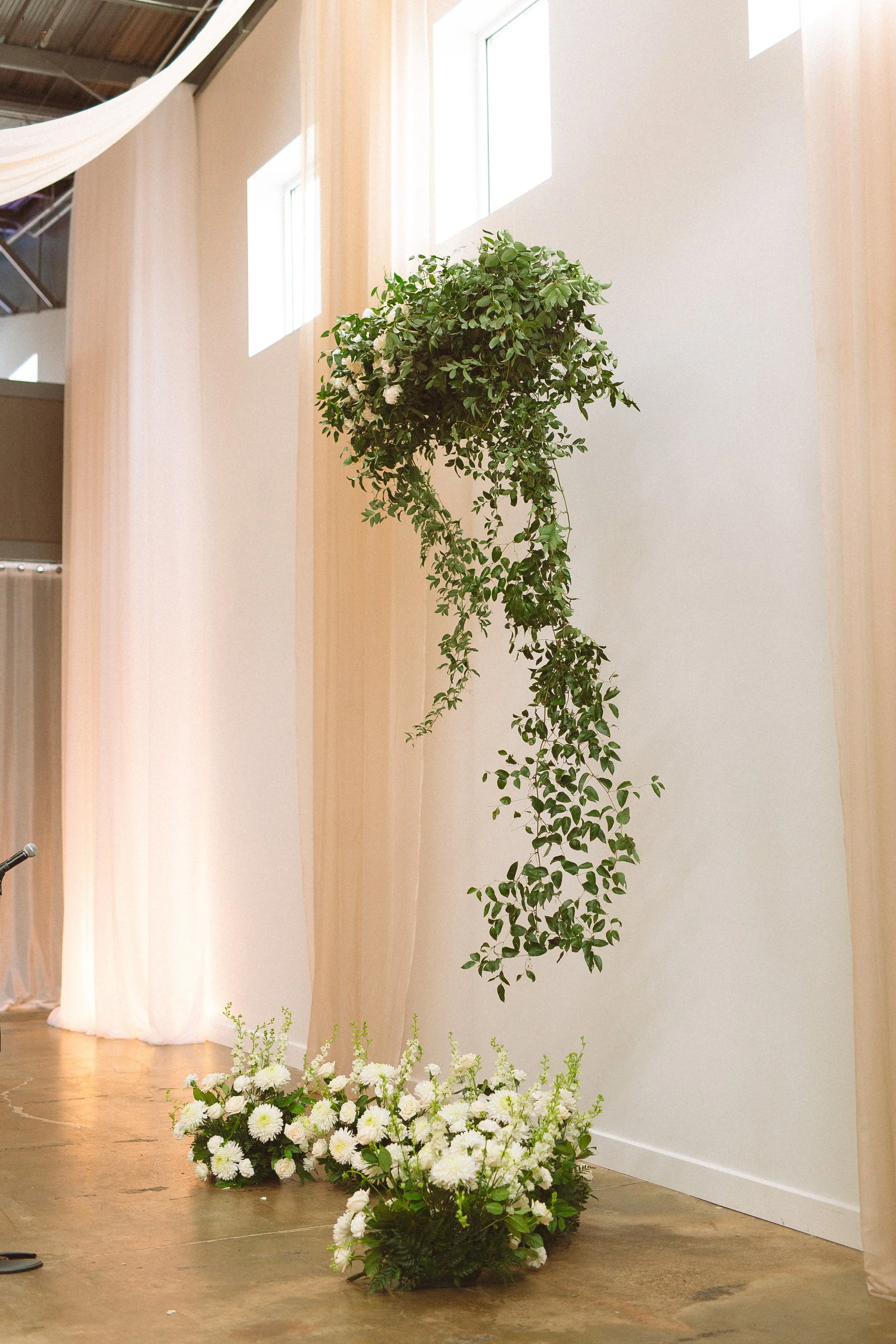 Champagne colored draping with white and green hanging florals for focal point.