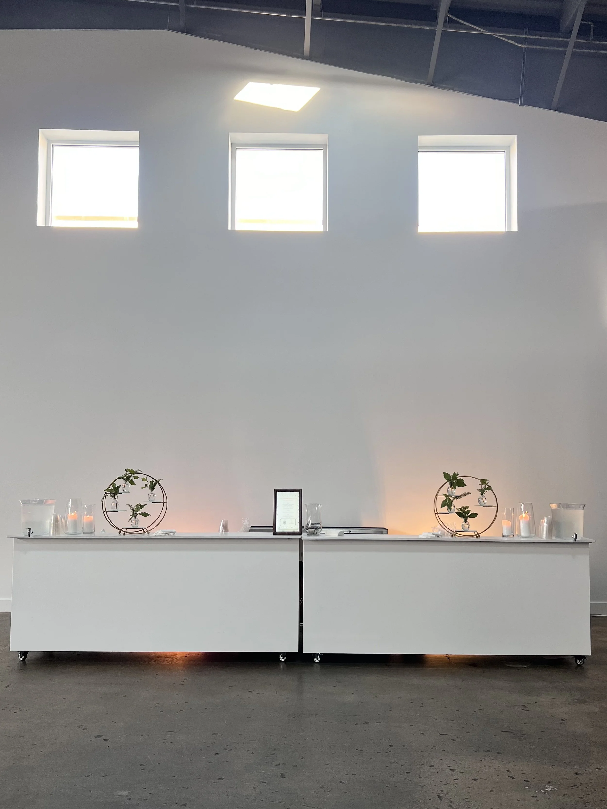 Image of white bar on white wall with white uplighting and tons of natural light filtering in from large windows.