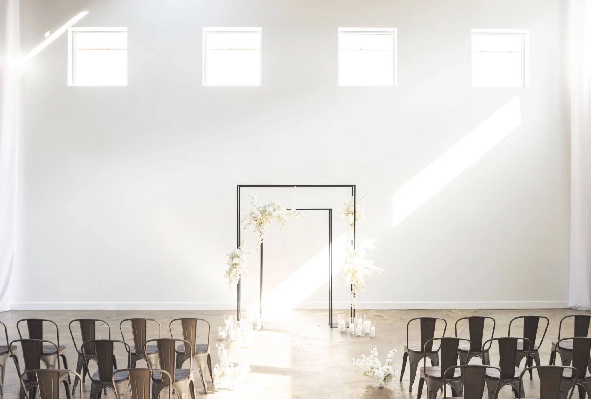 Black frame with white florals on a white wall with sunbeams streaming in.