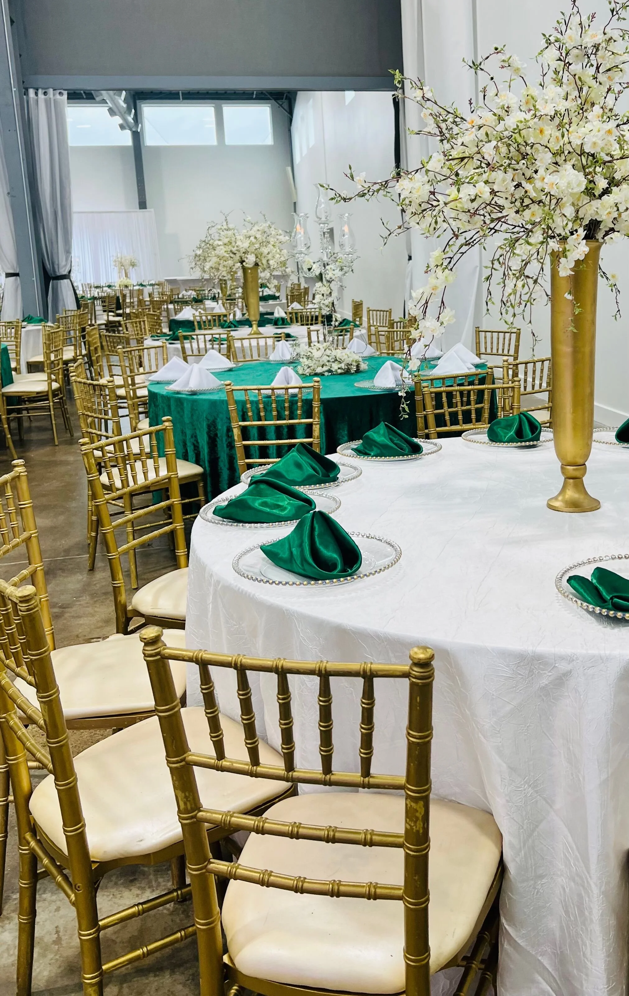 Chavari Gold Chairs, white linens, green napkins with gold vases and gold charges.