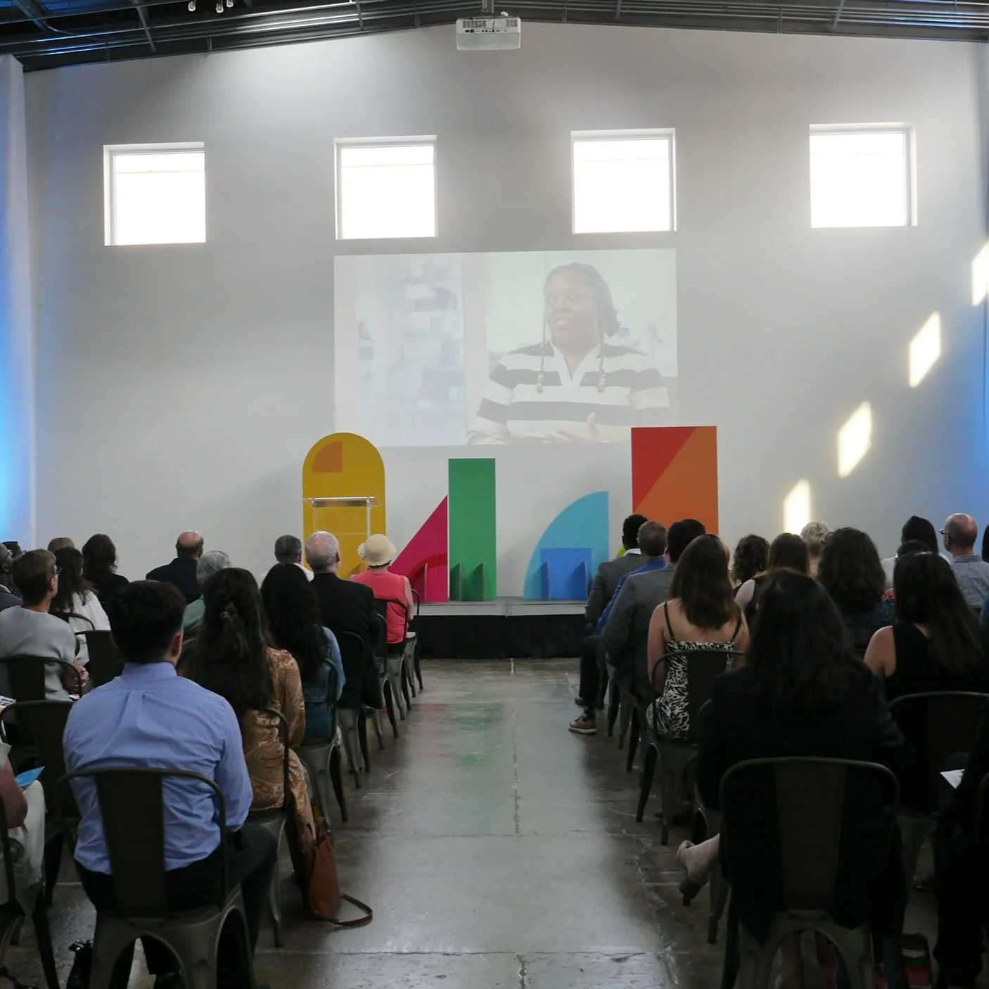 Presentation on large white wall with staging.