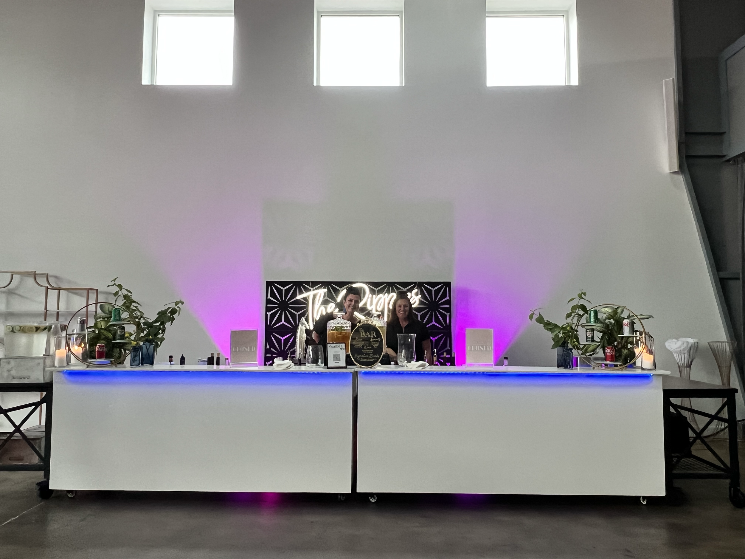 Bar with uplighting, 2 black panel frames and a last name neon sign.