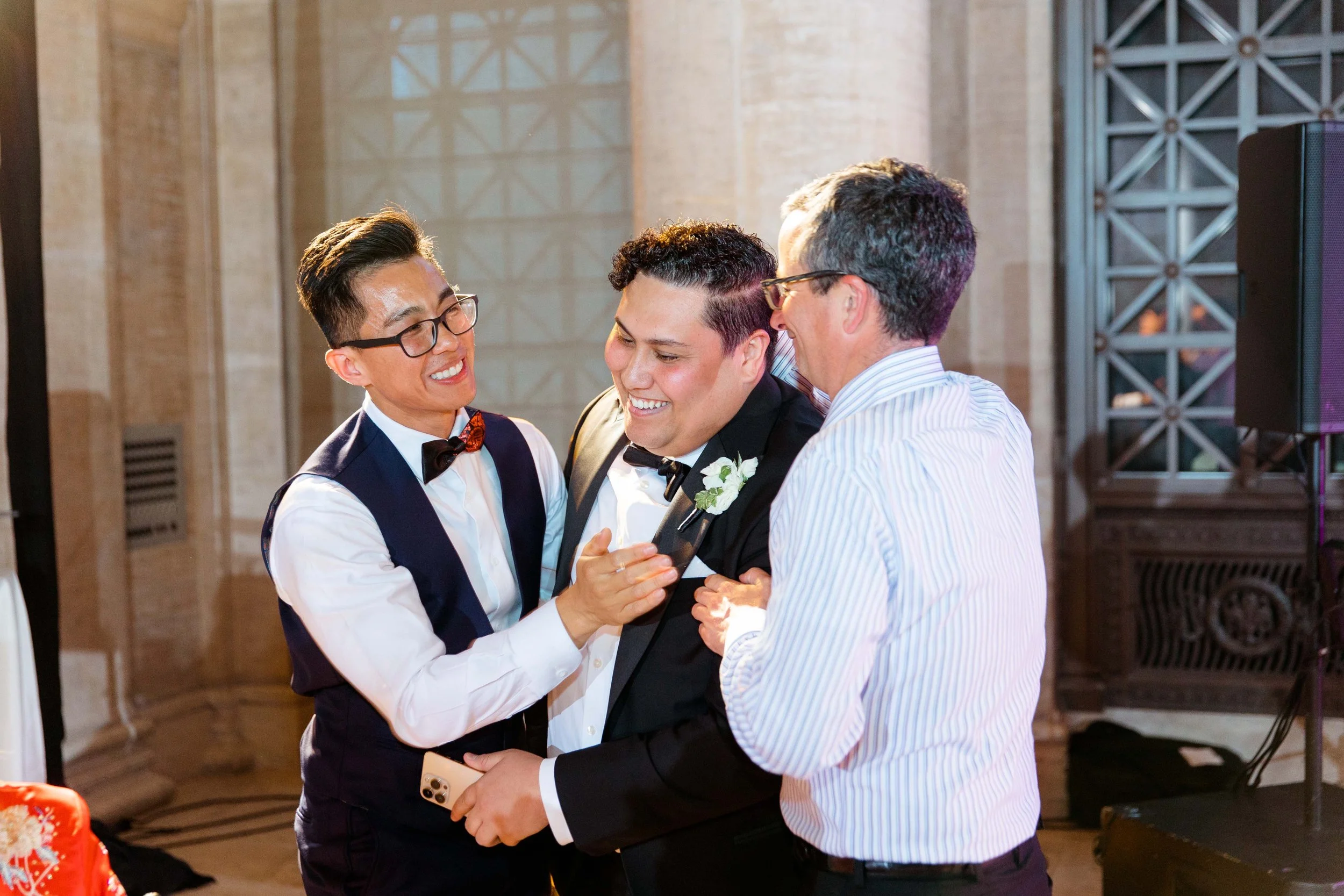 Four men celebrating at a formal event, smiling and embracing each other.