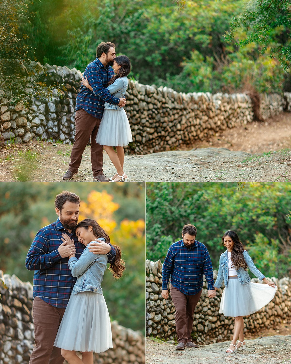 A couple sharing affectionate moments outdoors on a stone path surrounded by greenery and a stone wall. The woman wears a white tulle skirt and denim jacket, and the man wears a blue plaid shirt and brown pants. They're holding hands, hugging, and wa