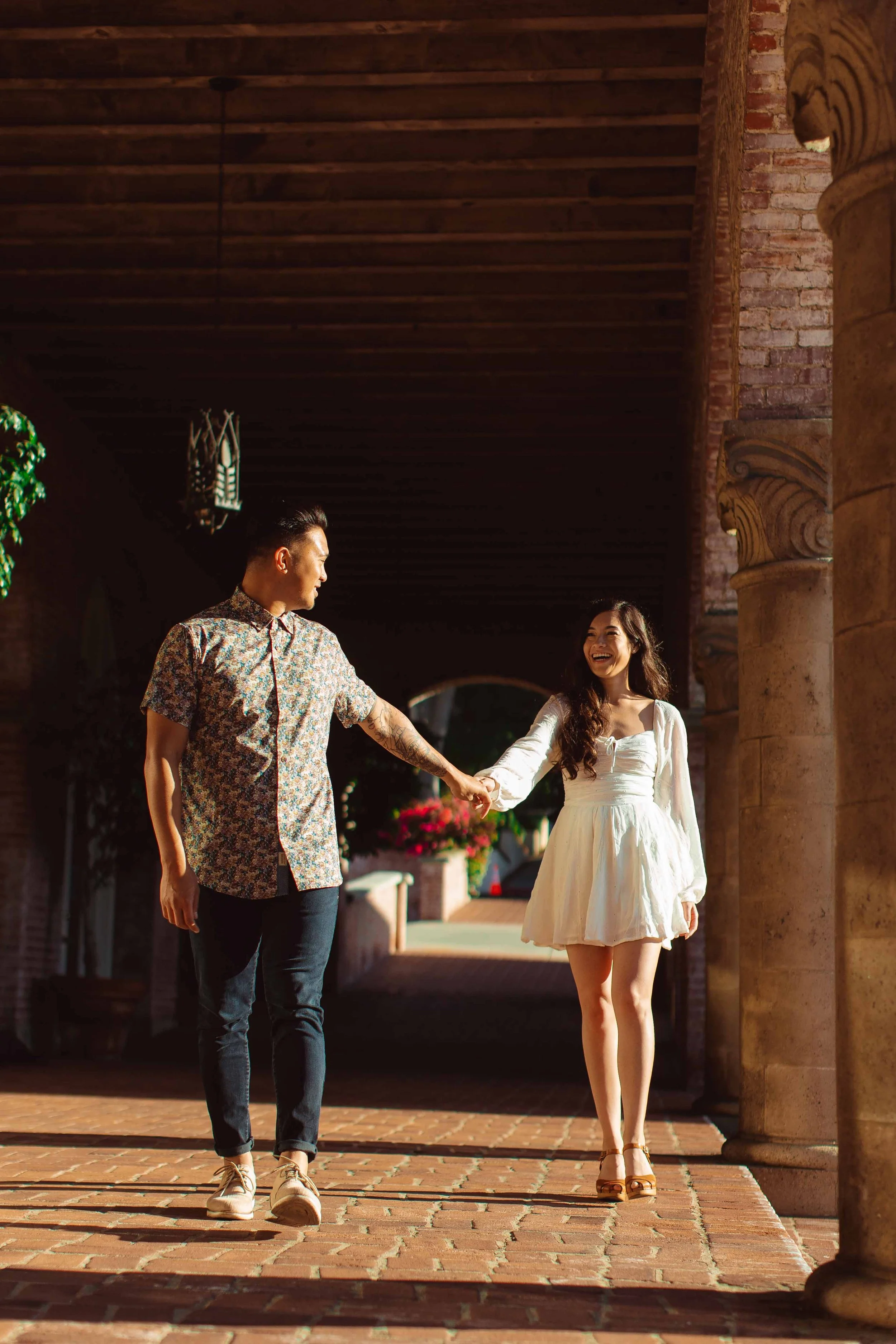 A man and woman holding hands and walking together outdoors, smiling and enjoying each other's company.