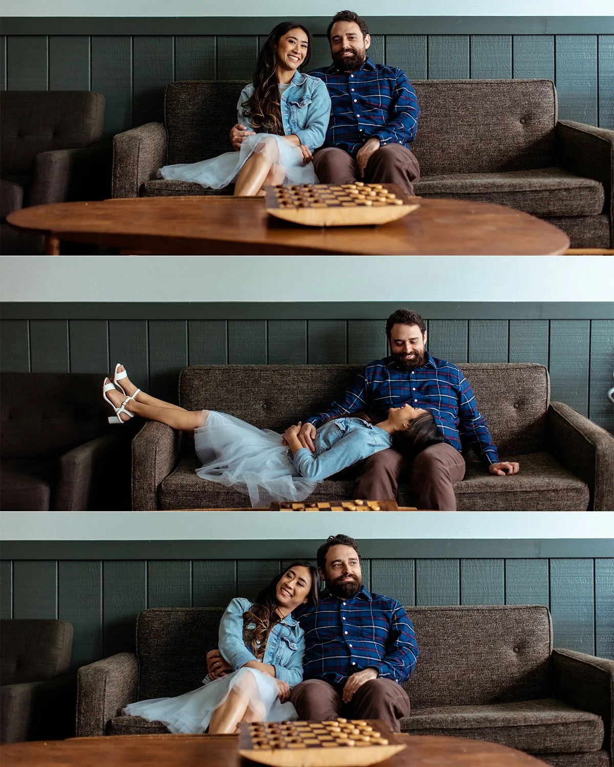 A man and woman sitting together on a couch in a living room, with a chessboard on the coffee table in front of them. The woman is wearing a light blue dress and denim jacket, smiling, and sitting close to the man, who is wearing a blue checkered shi