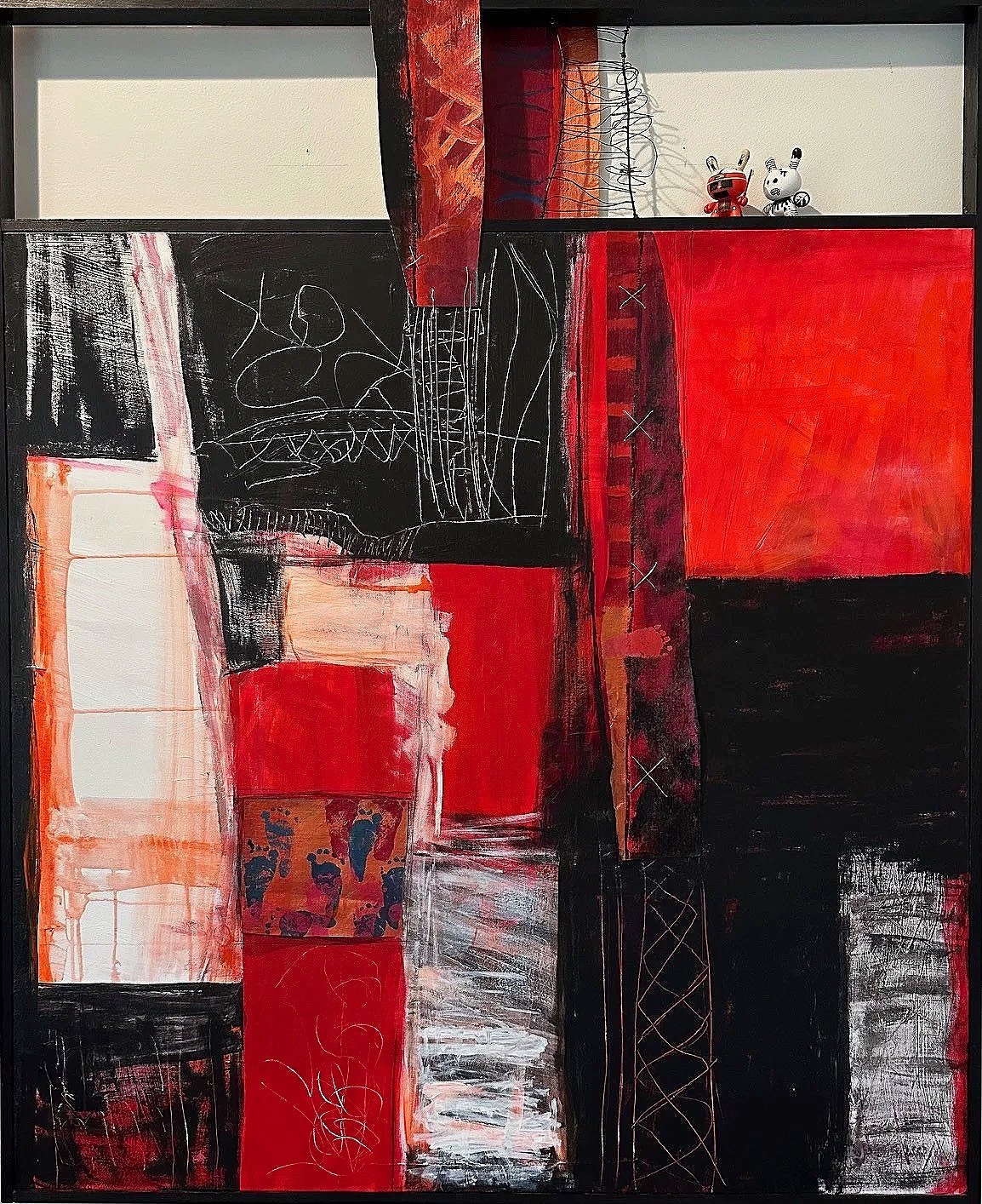 An abstract painting with red, black, and white blocks and lines, decorated with two small toy figures in the top right corner.