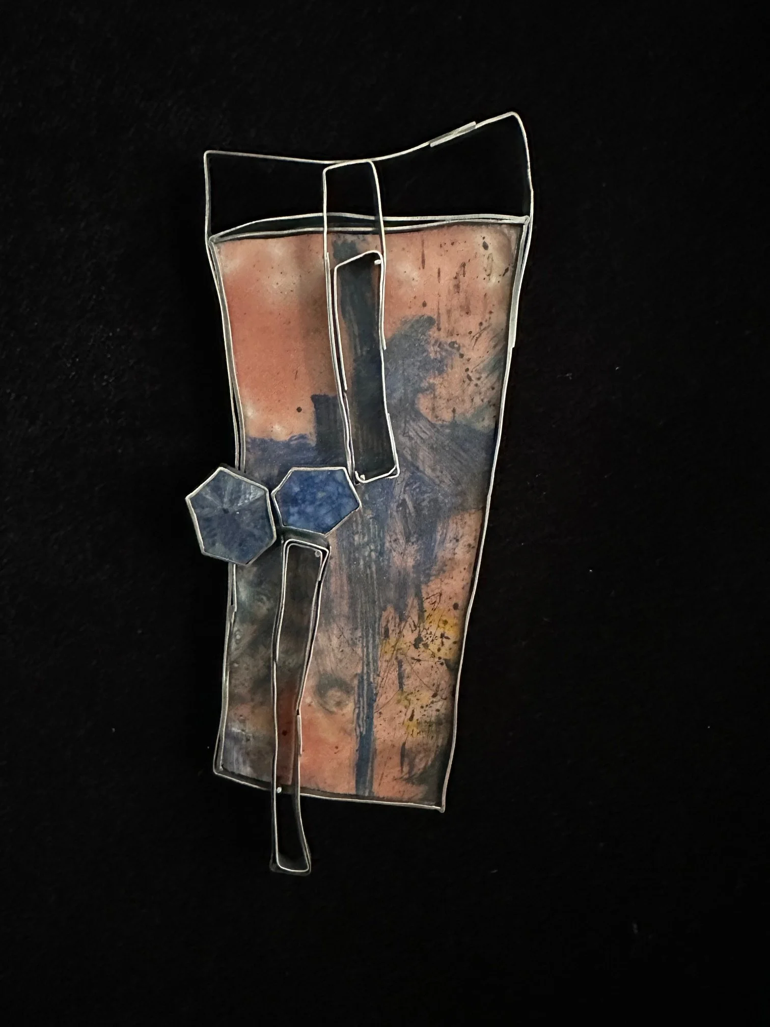 A metal wire sculpture of a beer glass with a brown beverage inside, placed on a black surface.