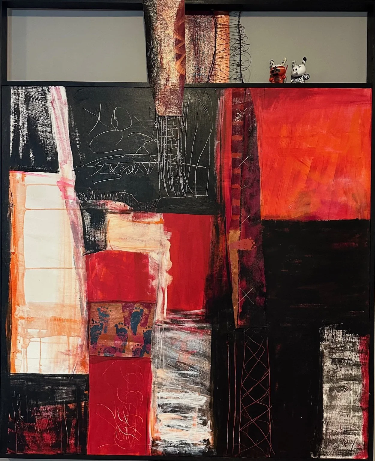 Abstract painting with geometric shapes and bold colors, predominantly red, black, and white, with some textured patterns and lines.