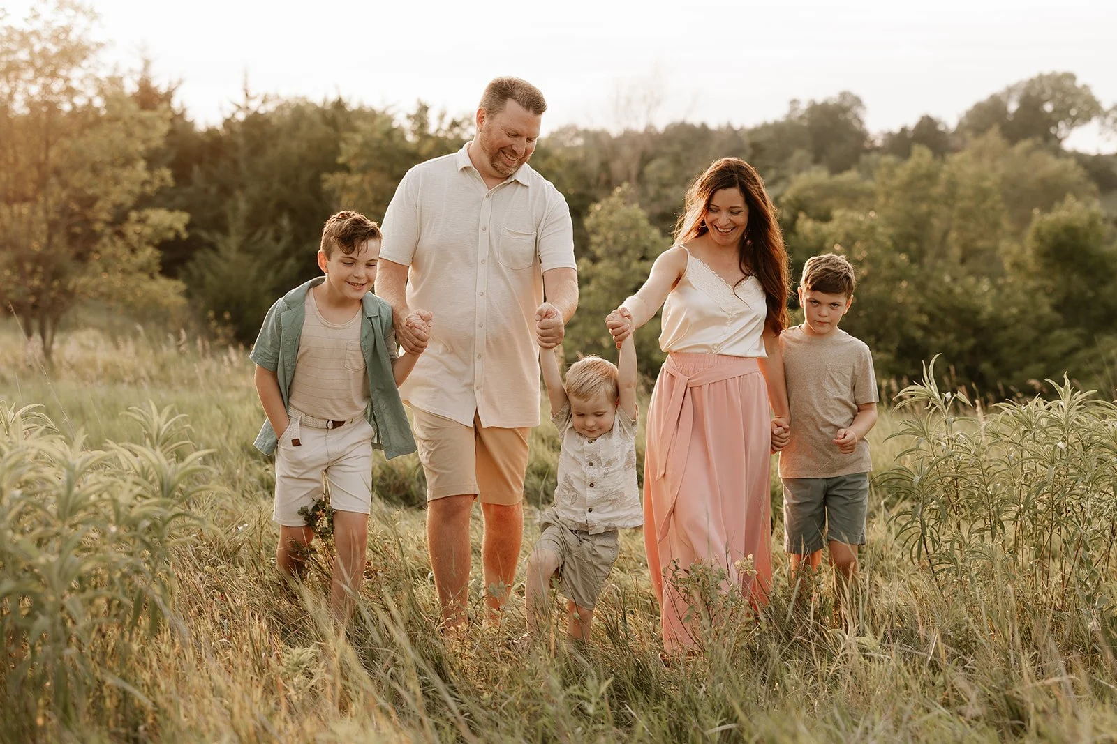 Kearney, NE mom, dad and three young boys walk through a field in style for their Nebraska family photos