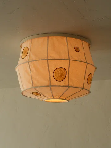 Ceiling light fixture with a fabric shade resembling a paper lantern with circular wood-like accents.