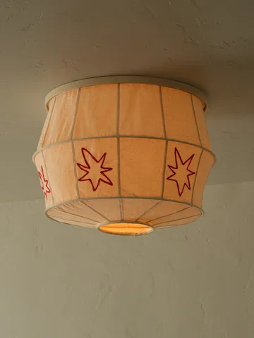 A ceiling lamp with a decorative lampshade featuring red starburst patterns.