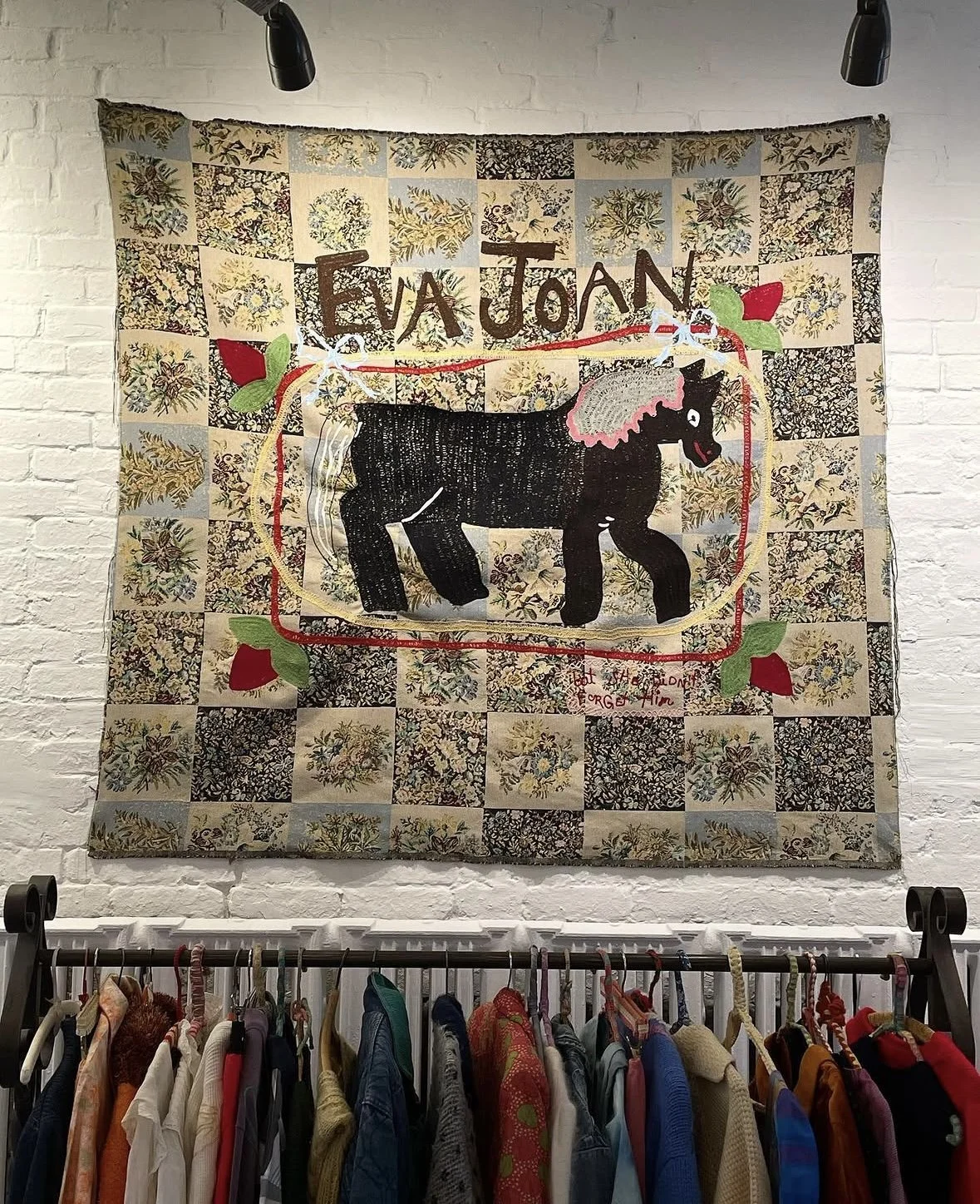 Decorative quilt with a black felt horse in the center, surrounded by leaves, flowers, and a red border. The quilt has the words 'EJA JoAN' at the top and a small red handwritten message at the bottom right.