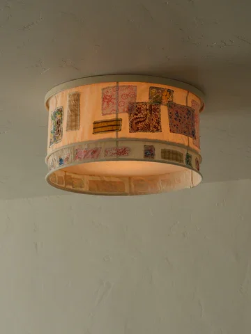 A circular ceiling light fixture with a decorative pattern on it, mounted on a white ceiling.