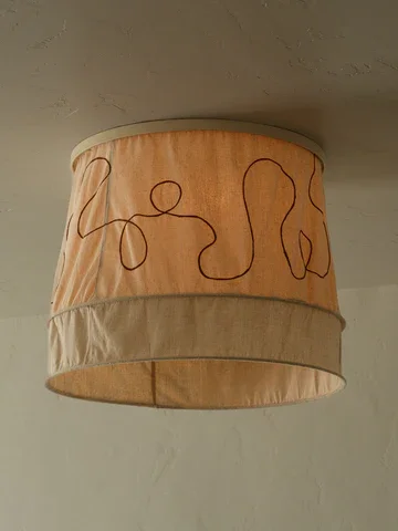 Ceiling lampshade with a beige fabric, featuring a simple abstract line drawing of a person.
