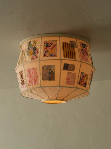 A ceiling light fixture with a fabric shade decorated with colorful quilt-like patchwork designs.