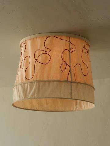 Ceiling light fixture with a beige fabric lampshade featuring brown embroidered squiggly lines.