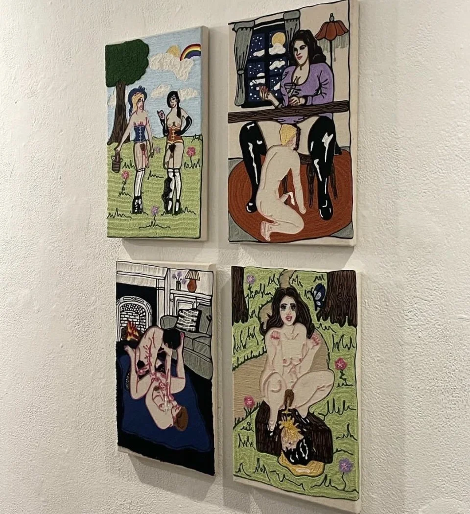 Four colorful paintings on a white wall, featuring women in various settings and poses, including two in outdoor scenes, one indoors with a view of the night sky, and one sitting near trees with a butterfly nearby.