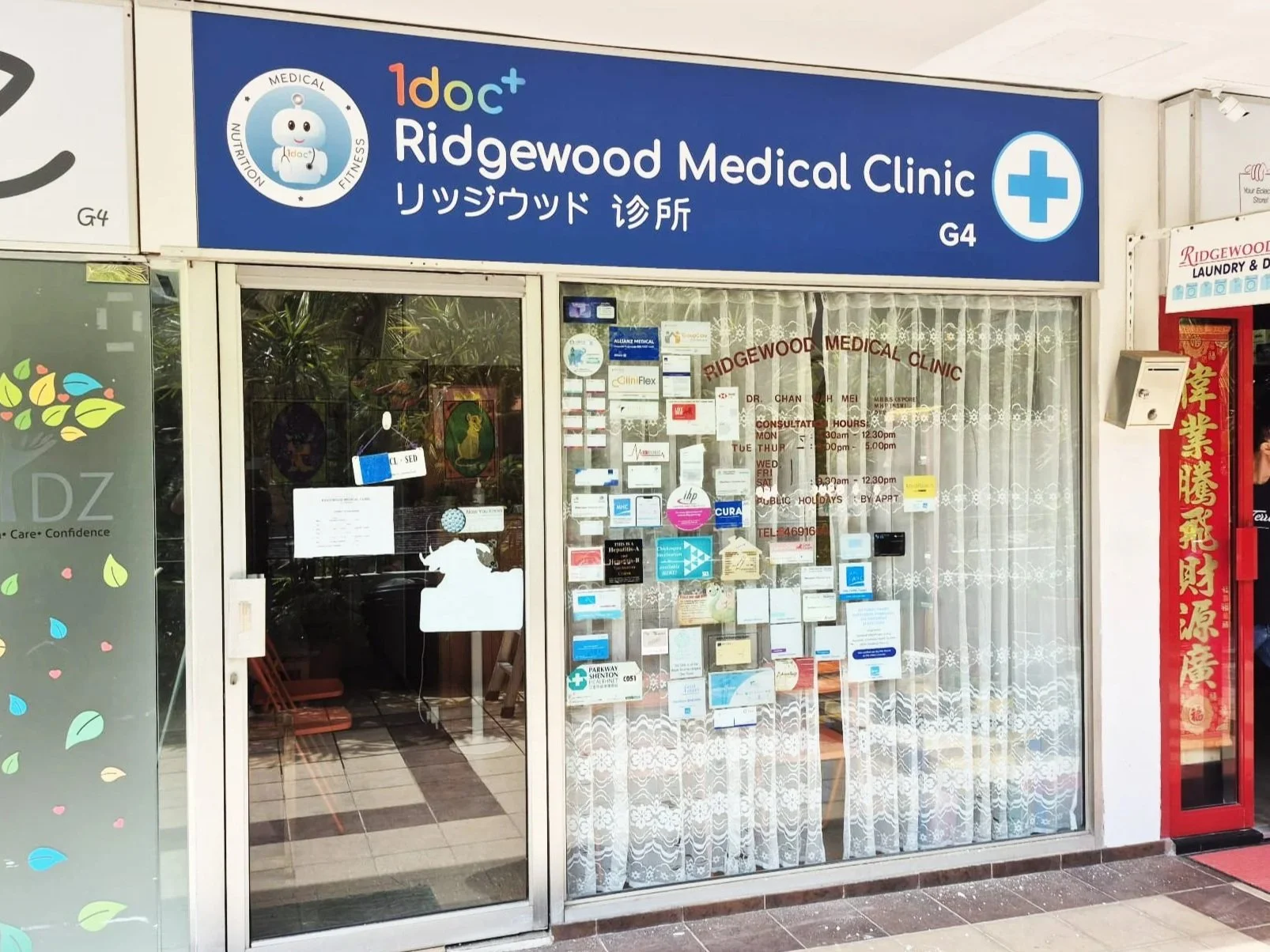 Facade of Ridgewood Medical Clinic with glass door and window covered with notices, and a blue sign with white text and a medical cross symbol on top.