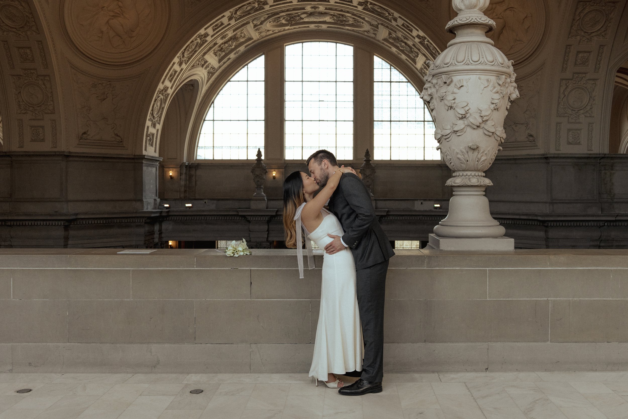 A bride and groom kissing at San Francisco City Hall during their courthouse wedding ceremony