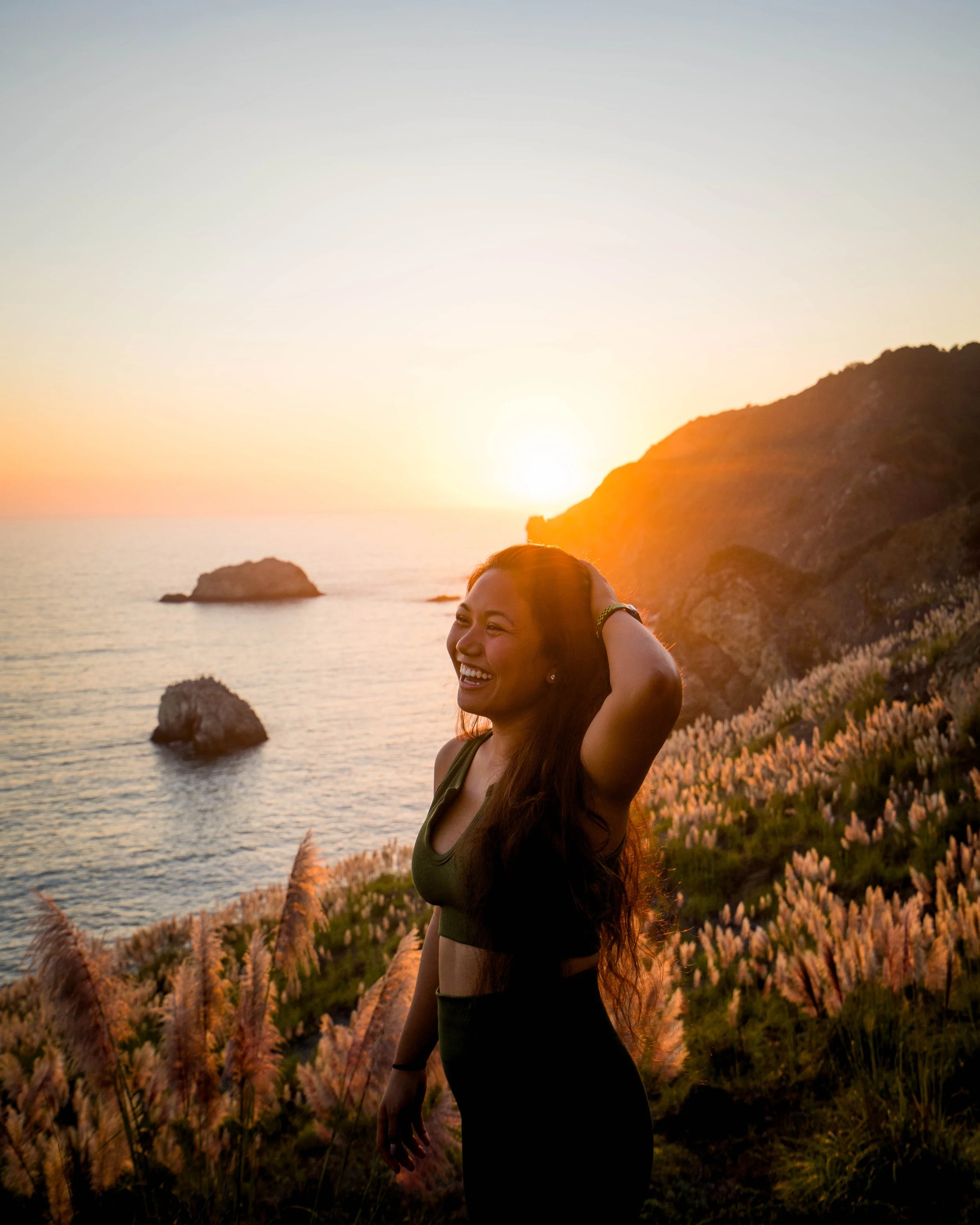 Sunset portrait of a woman standing on a hillside overlooking the ocean near Mount Tamalpais in San Francisco Bay Area