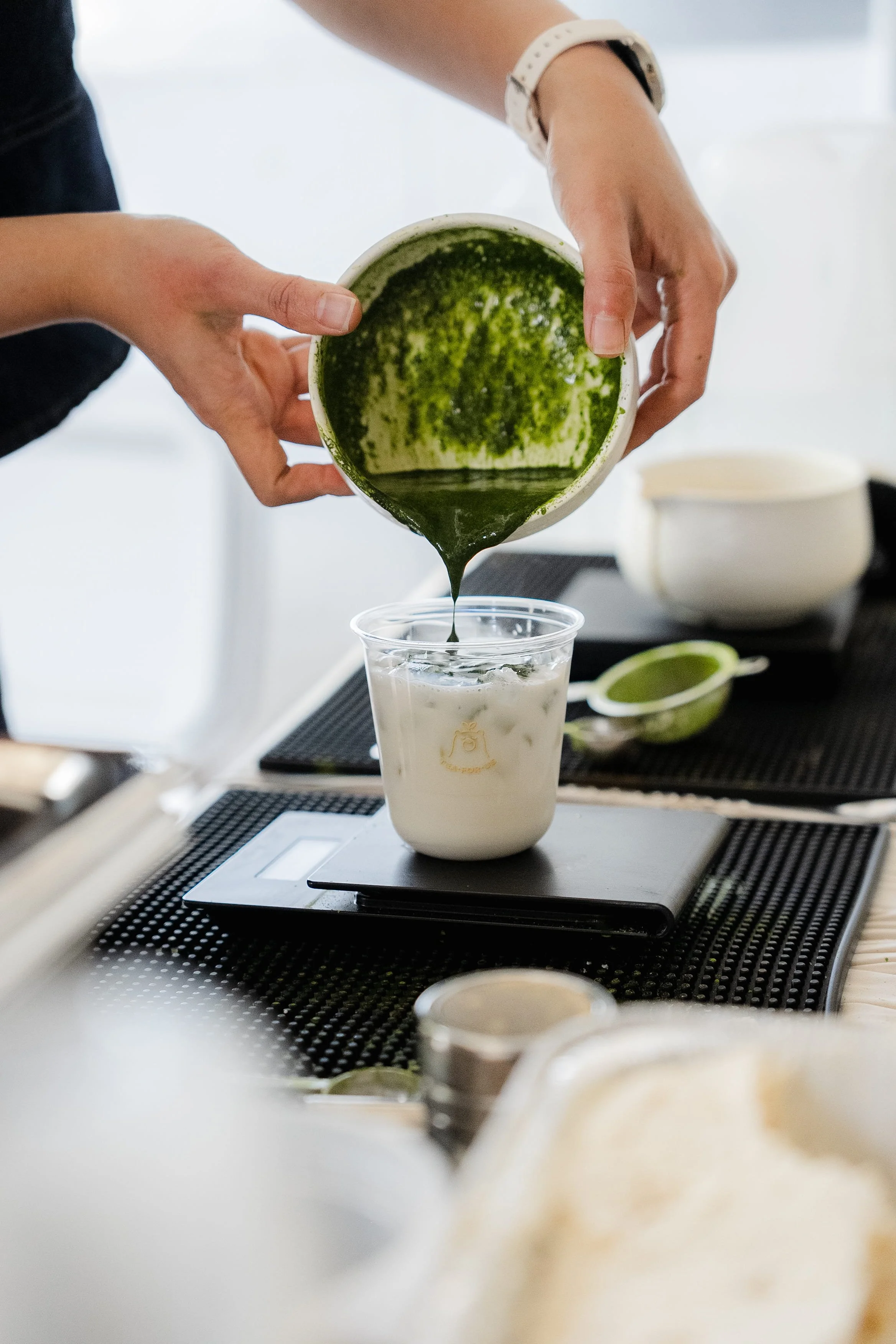 Close up action shot of matcha being poured into a cup of milk during a Tea For Us brand activation pop-up with Kindred Studio in San Francisco