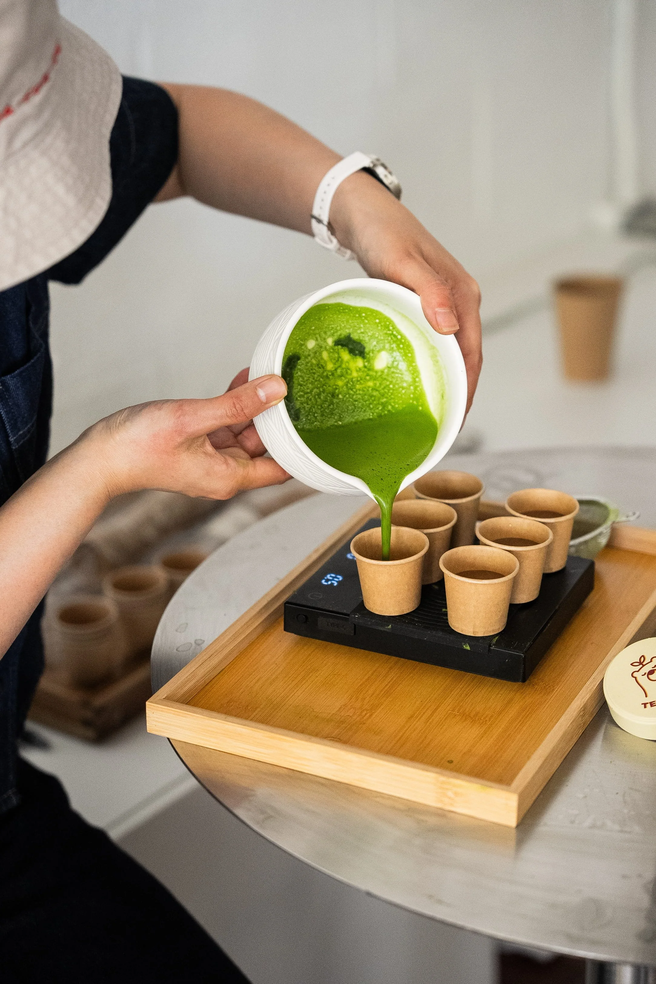 Action shot of brand owner measuring matcha tasting cups during a Tea For Us brand activation pop-up with Kindred Studio in San Francisco