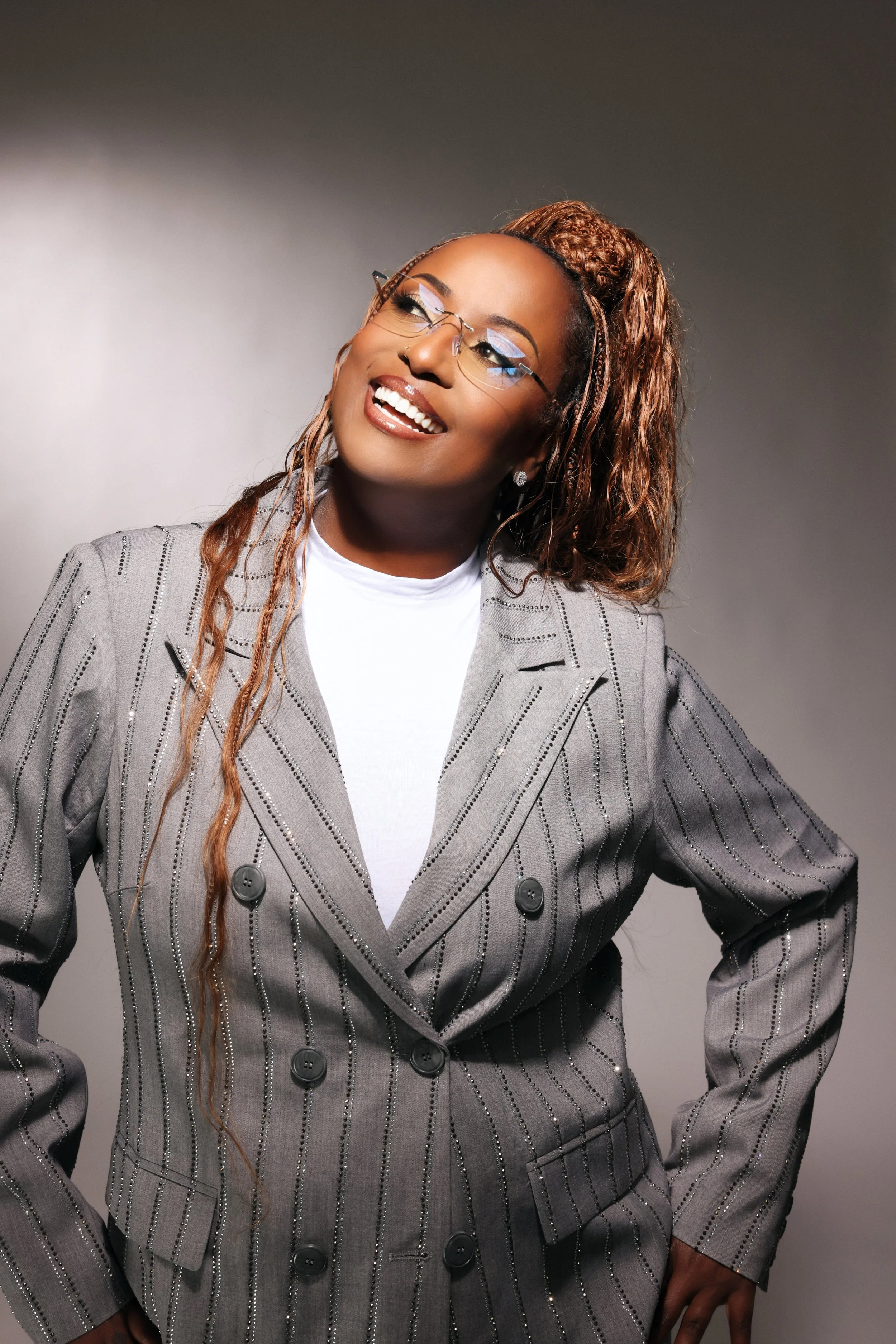 Miss Andye J smiling in a gray suit and glasse