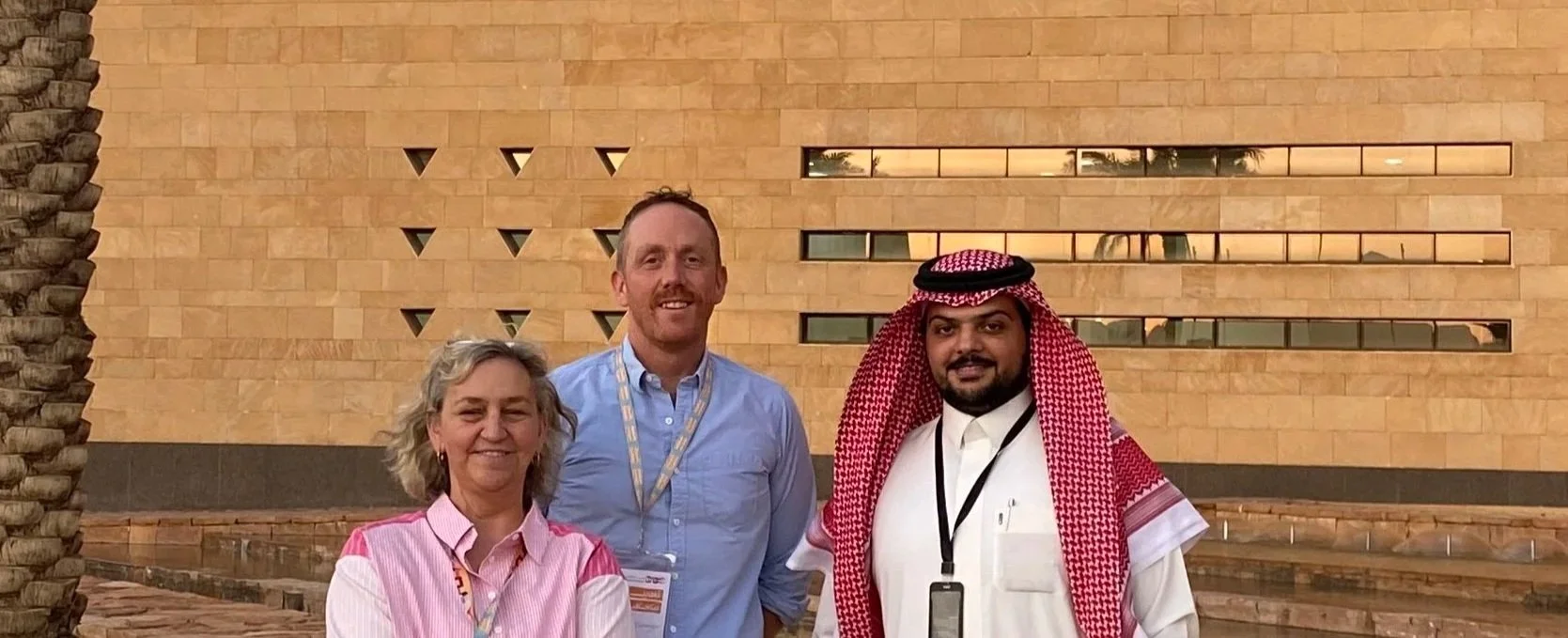 Three people standing together outdoors in front of a modern stone building.