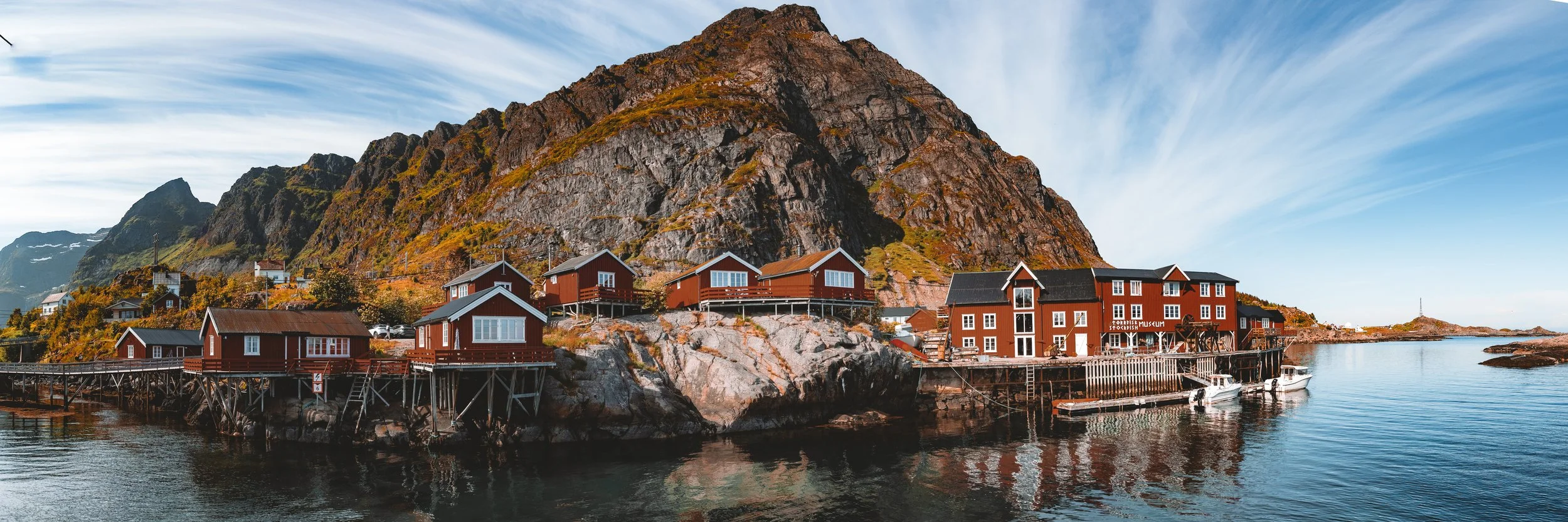 Panoramic view of Å in the Lofoten Islands, Norway, with red coastal buildings, mountains, rocks and sea.